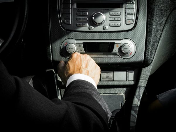 pexels-photo-1135379-1135379 Close-up of a driver in a suit operating the car dashboard controls, capturing a professional interior setting.